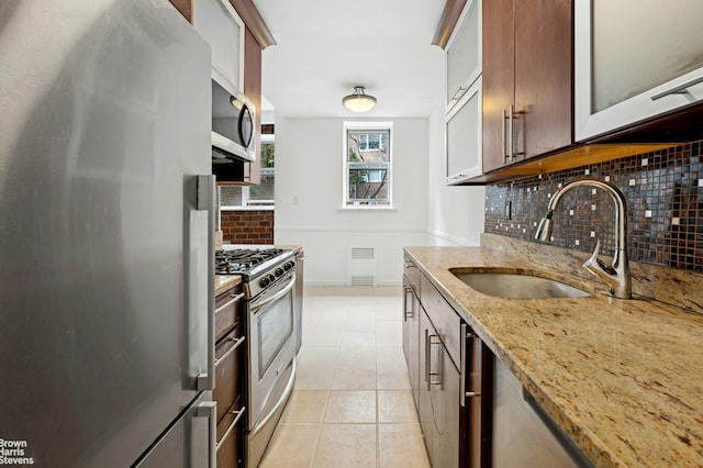 kitchen with visible vents, a sink, light stone counters, stainless steel appliances, and light tile patterned floors