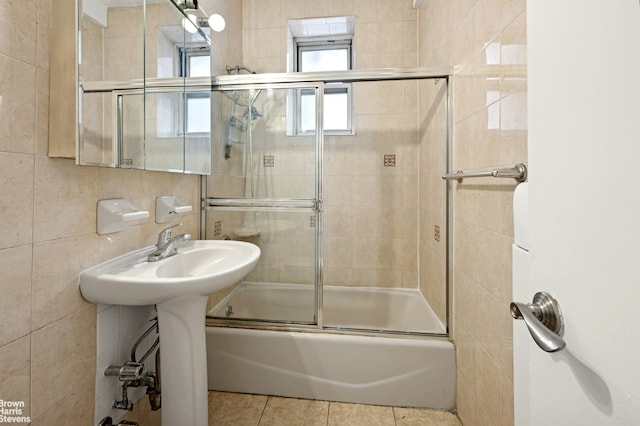 full bath featuring tile patterned floors, tile walls, and bath / shower combo with glass door