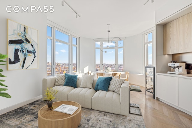 living room with an inviting chandelier, track lighting, a view of city, and baseboards