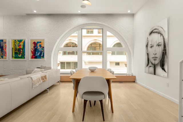 dining space featuring recessed lighting, light wood-type flooring, and brick wall