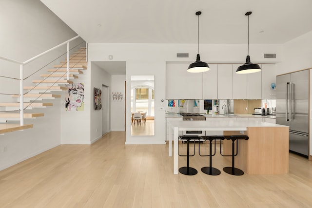 kitchen featuring light wood-style flooring, light countertops, built in fridge, a kitchen breakfast bar, and modern cabinets