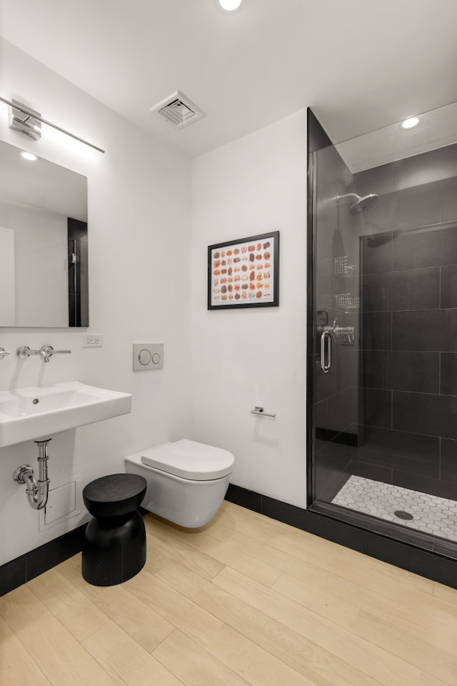 bathroom featuring visible vents, baseboards, toilet, a stall shower, and wood finished floors