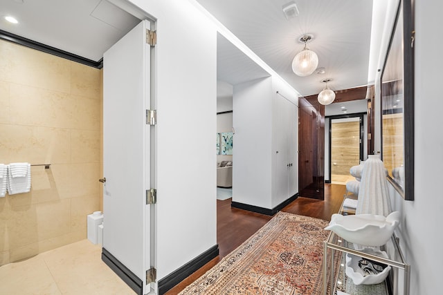 hallway with tile walls and wood finished floors