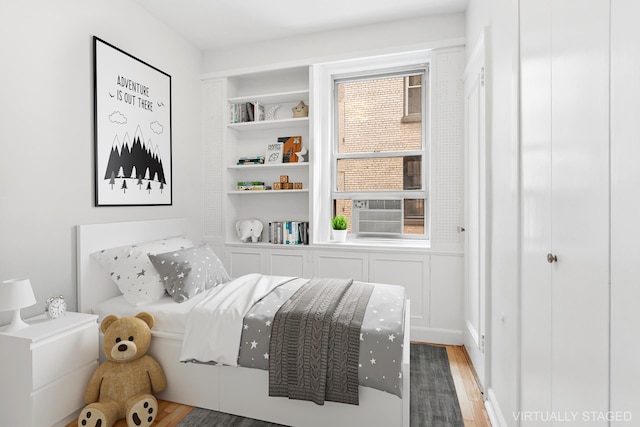 bedroom featuring wood finished floors and cooling unit