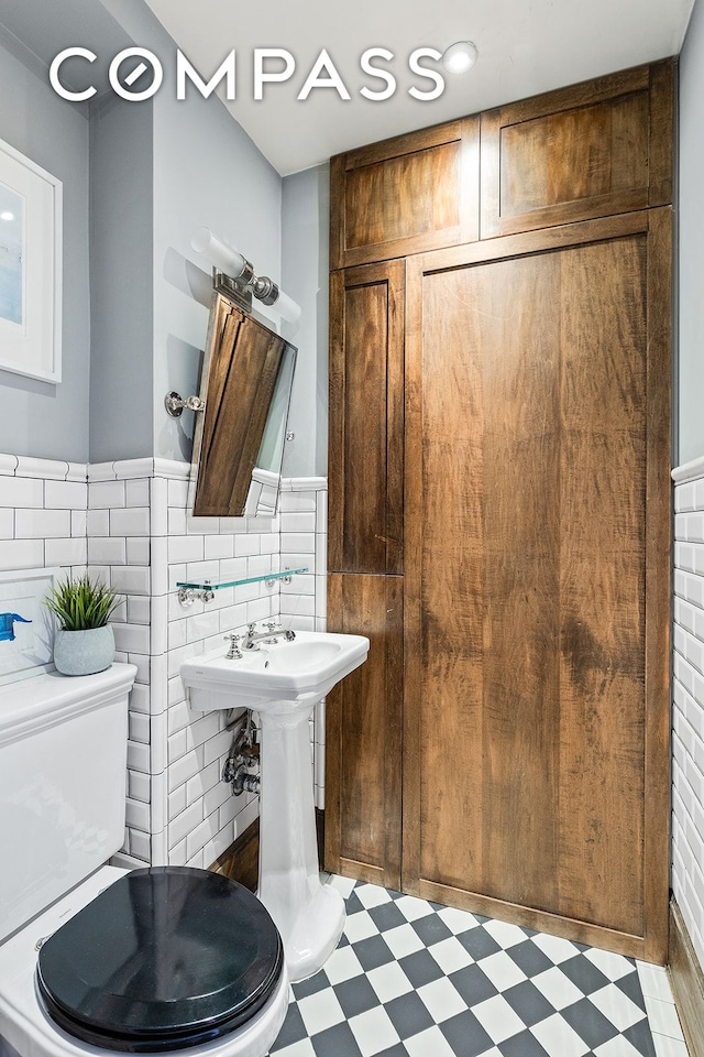 bathroom with tile patterned floors, toilet, and tile walls