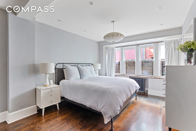 bedroom with radiator, baseboards, and wood finished floors