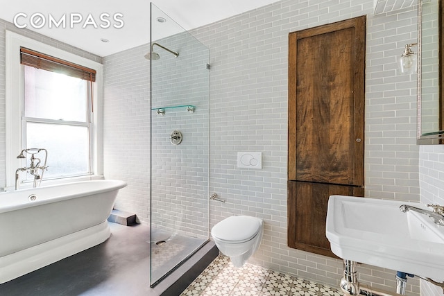 full bath featuring a freestanding bath, tile walls, a tile shower, and a sink