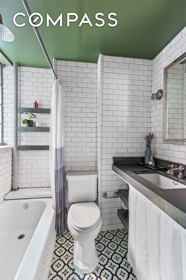 bathroom featuring vanity, shower / bathtub combination with curtain, tile walls, toilet, and tile patterned floors