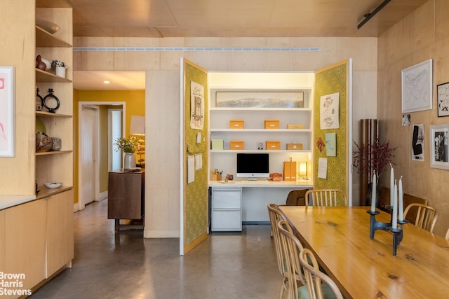 dining space with baseboards, built in shelves, finished concrete floors, and built in study area