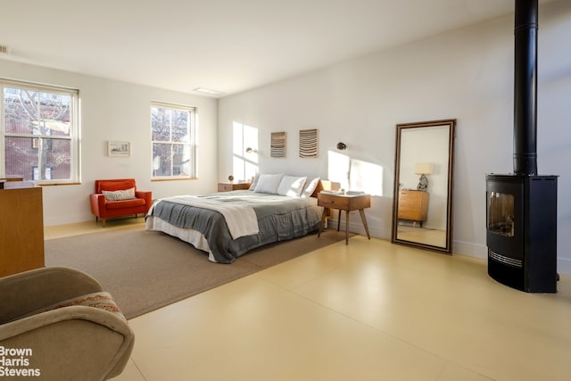 bedroom featuring visible vents, a wood stove, and baseboards