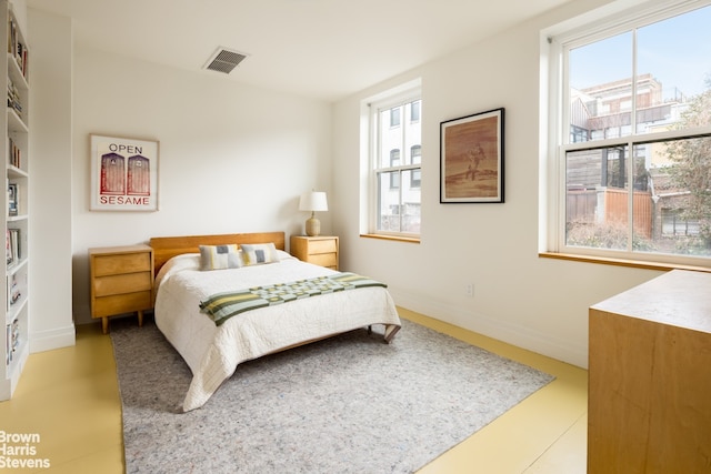 bedroom featuring visible vents, multiple windows, and baseboards