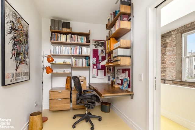 office space featuring baseboards and brick wall