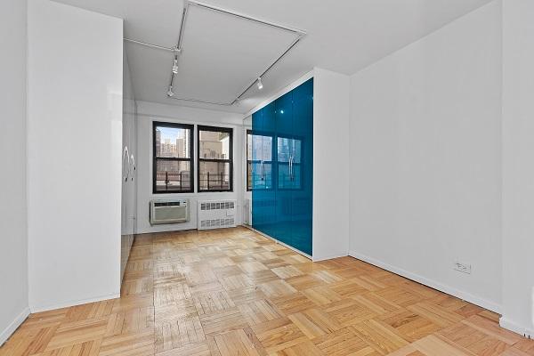 spare room featuring a wall mounted AC, radiator, rail lighting, baseboards, and attic access