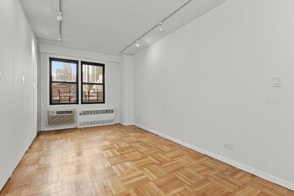 empty room with track lighting, radiator, a wall mounted air conditioner, and baseboards