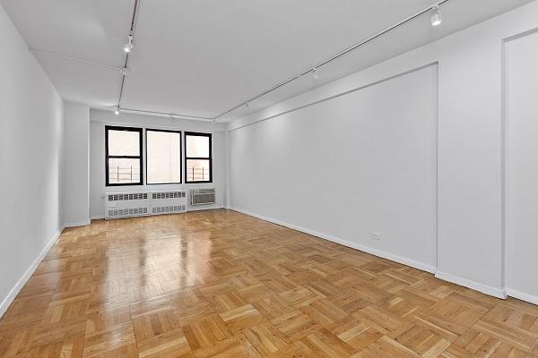 empty room with track lighting, a wall mounted AC, radiator heating unit, and baseboards