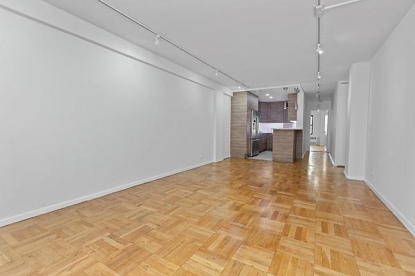 unfurnished living room with rail lighting and baseboards