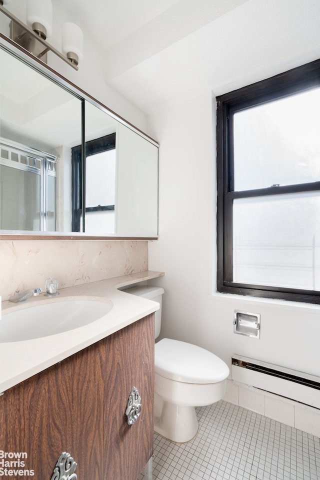 bathroom featuring a baseboard heating unit, toilet, plenty of natural light, and tile patterned flooring