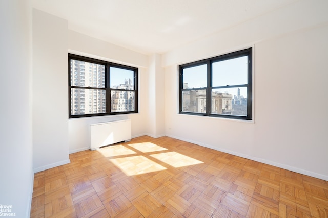 spare room with baseboards, a view of city, and radiator heating unit