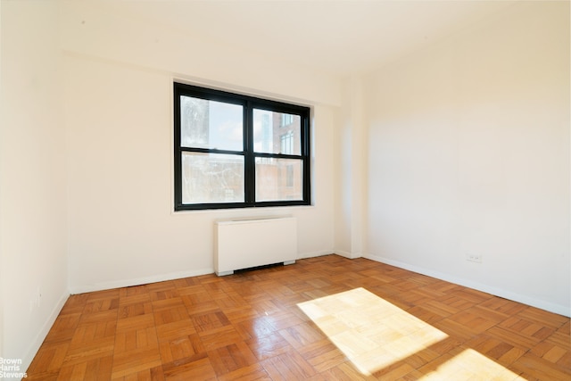 unfurnished room featuring radiator heating unit and baseboards