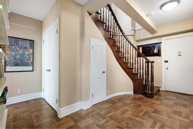 foyer featuring baseboards and stairs