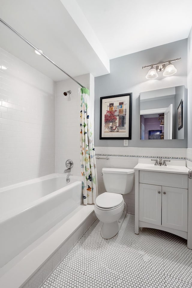 full bath with vanity, shower / bath combination with curtain, wainscoting, tile walls, and toilet