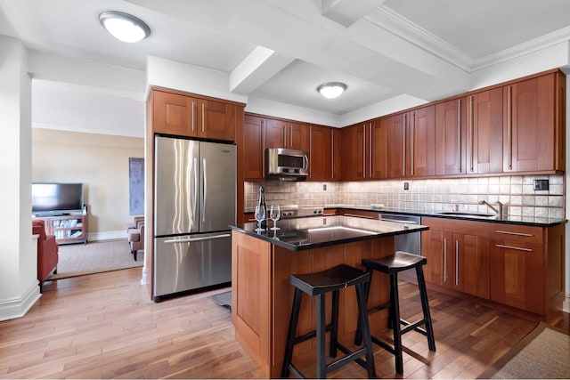 kitchen featuring light wood-style flooring, dark countertops, a breakfast bar area, stainless steel appliances, and a sink