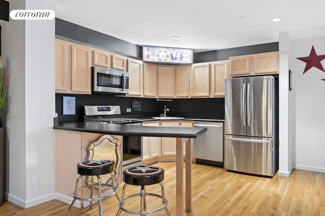 kitchen with stainless steel appliances, light brown cabinets, a sink, baseboards, and recessed lighting