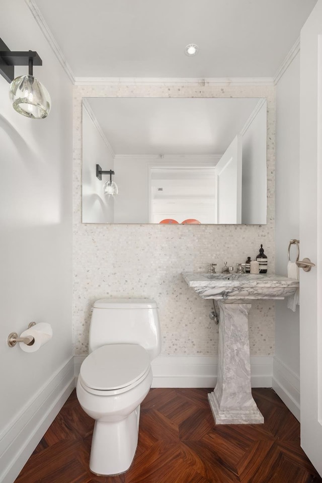 bathroom with baseboards, toilet, and crown molding