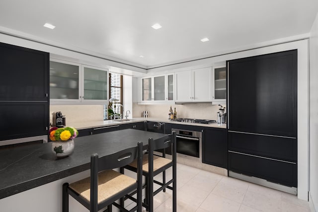 kitchen with light tile patterned floors, white cabinetry, a sink, appliances with stainless steel finishes, and dark cabinetry