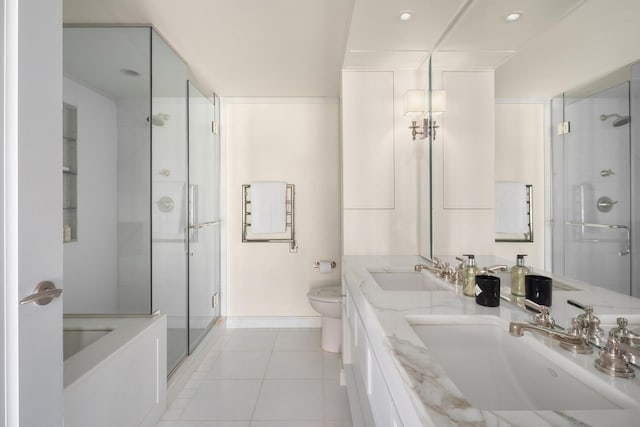 bathroom featuring toilet, a stall shower, a sink, and tile patterned floors