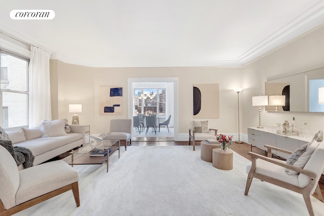 living area with light wood-type flooring, plenty of natural light, visible vents, and ornamental molding