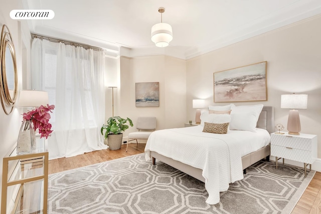 bedroom featuring wood finished floors and ornamental molding