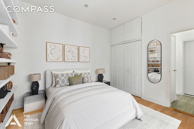 bedroom featuring a closet, light wood-style flooring, and baseboards