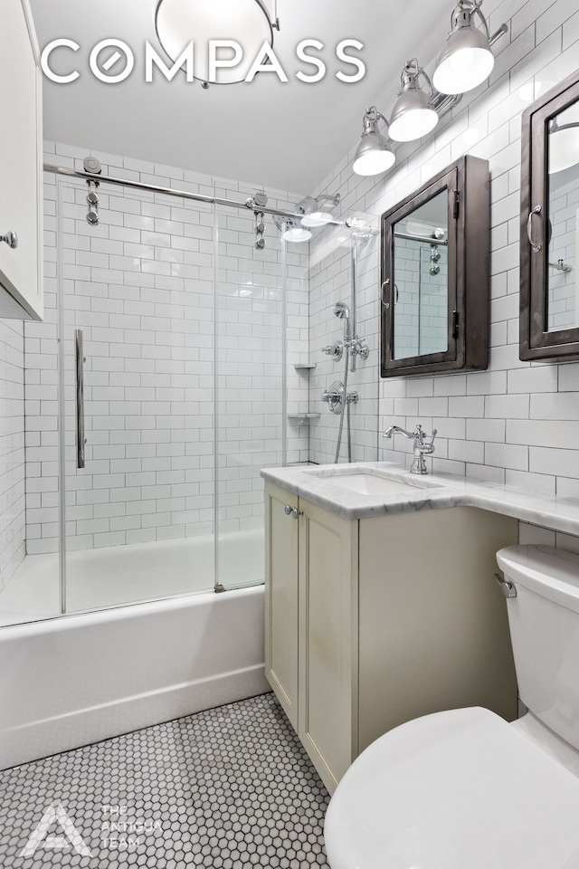 full bathroom featuring vanity, tile walls, toilet, combined bath / shower with glass door, and backsplash