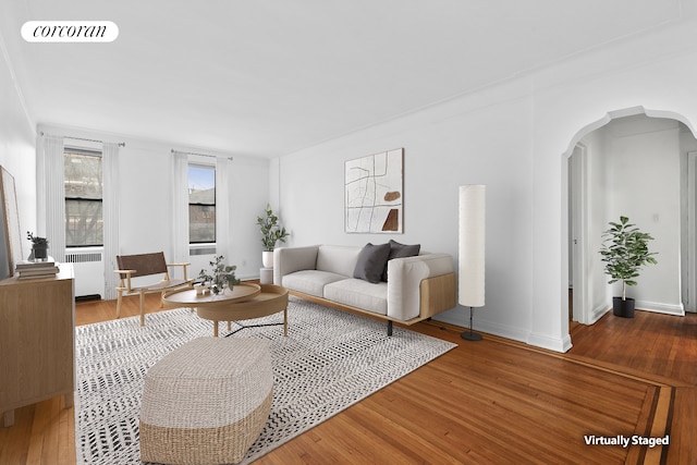 living room with radiator, visible vents, baseboards, arched walkways, and hardwood / wood-style flooring