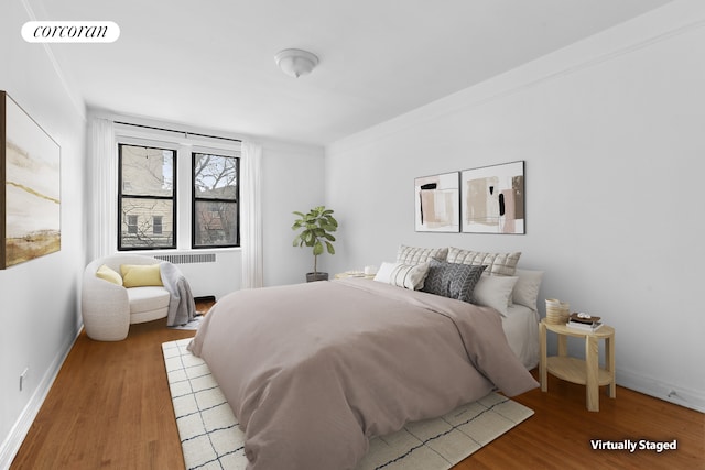 bedroom with visible vents, radiator, baseboards, and wood finished floors