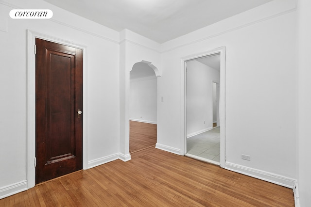 spare room with arched walkways, visible vents, light wood finished floors, and baseboards