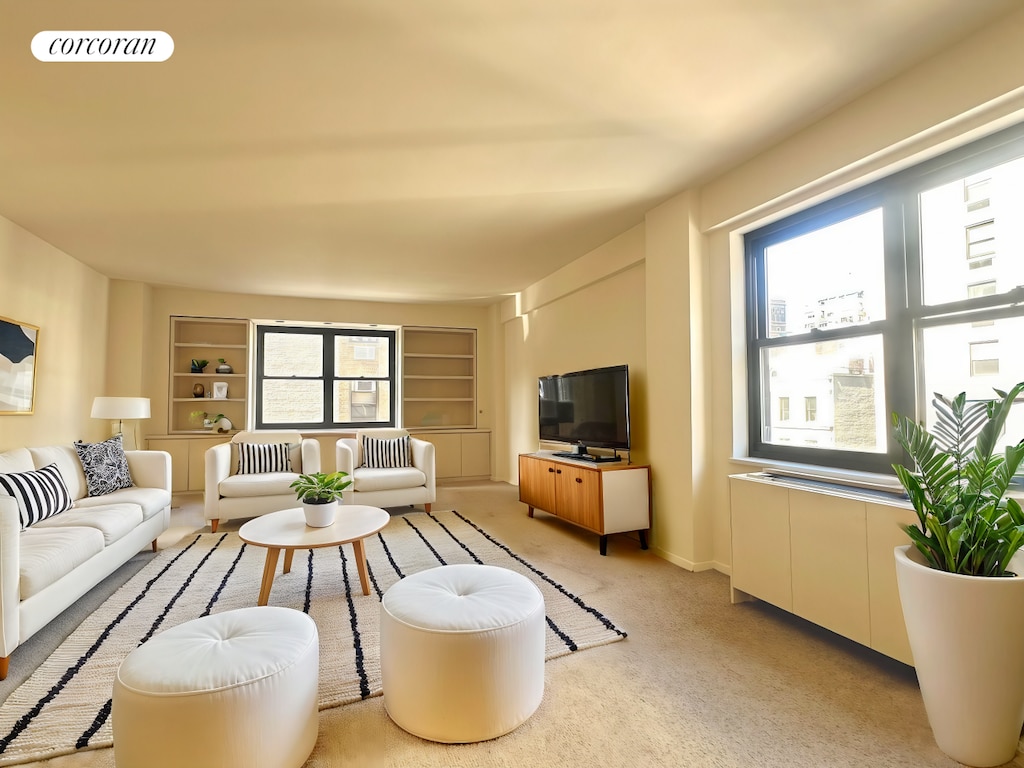 living room with built in features, visible vents, and light colored carpet