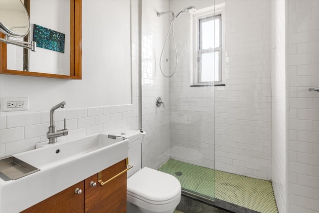 bathroom featuring vanity, a shower stall, toilet, and tile walls