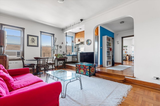 living room featuring crown molding, cooling unit, baseboards, and arched walkways