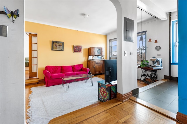 living area featuring electric panel, arched walkways, crown molding, and baseboards