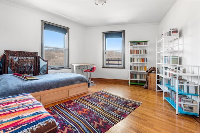 bedroom with multiple windows, wood finished floors, and ornamental molding