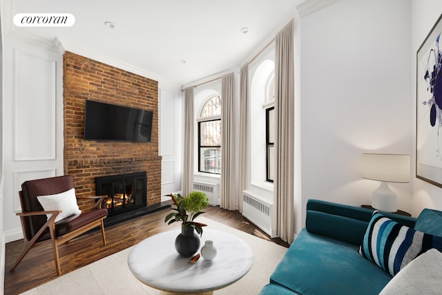 living room with visible vents, a fireplace, radiator heating unit, and wood finished floors