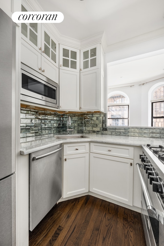 kitchen with a sink, tasteful backsplash, dark wood finished floors, appliances with stainless steel finishes, and white cabinets