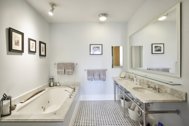 bathroom featuring tile patterned floors, a whirlpool tub, baseboards, and a sink