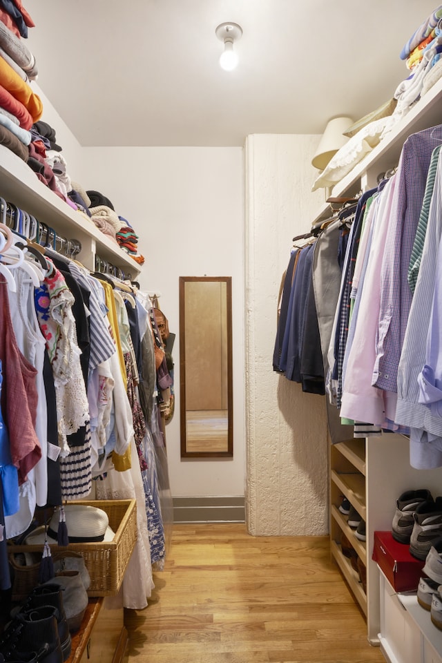 walk in closet with light wood-style floors