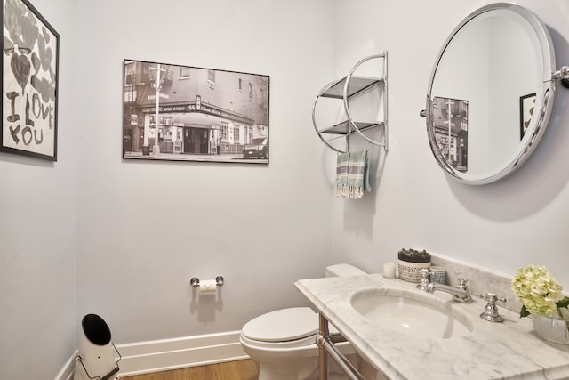 bathroom with baseboards, toilet, wood finished floors, and vanity