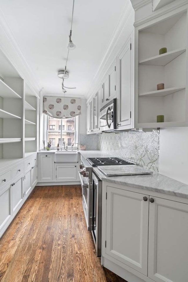 400 E 59th St Unit 4C, New York City, NY 10022 - kitchen with open shelves, stainless steel appliances, a sink, dark wood-style floors, and ornamental molding