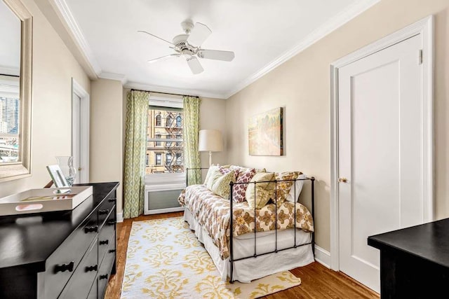 bedroom featuring crown molding, baseboards, light wood finished floors, and ceiling fan