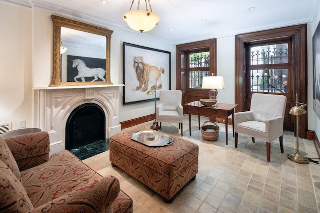living area with a fireplace with flush hearth, baseboards, and crown molding